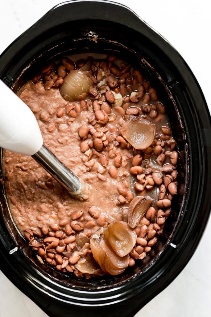 Puréeing pinto beans in a Crock-Pot using a hand blender.